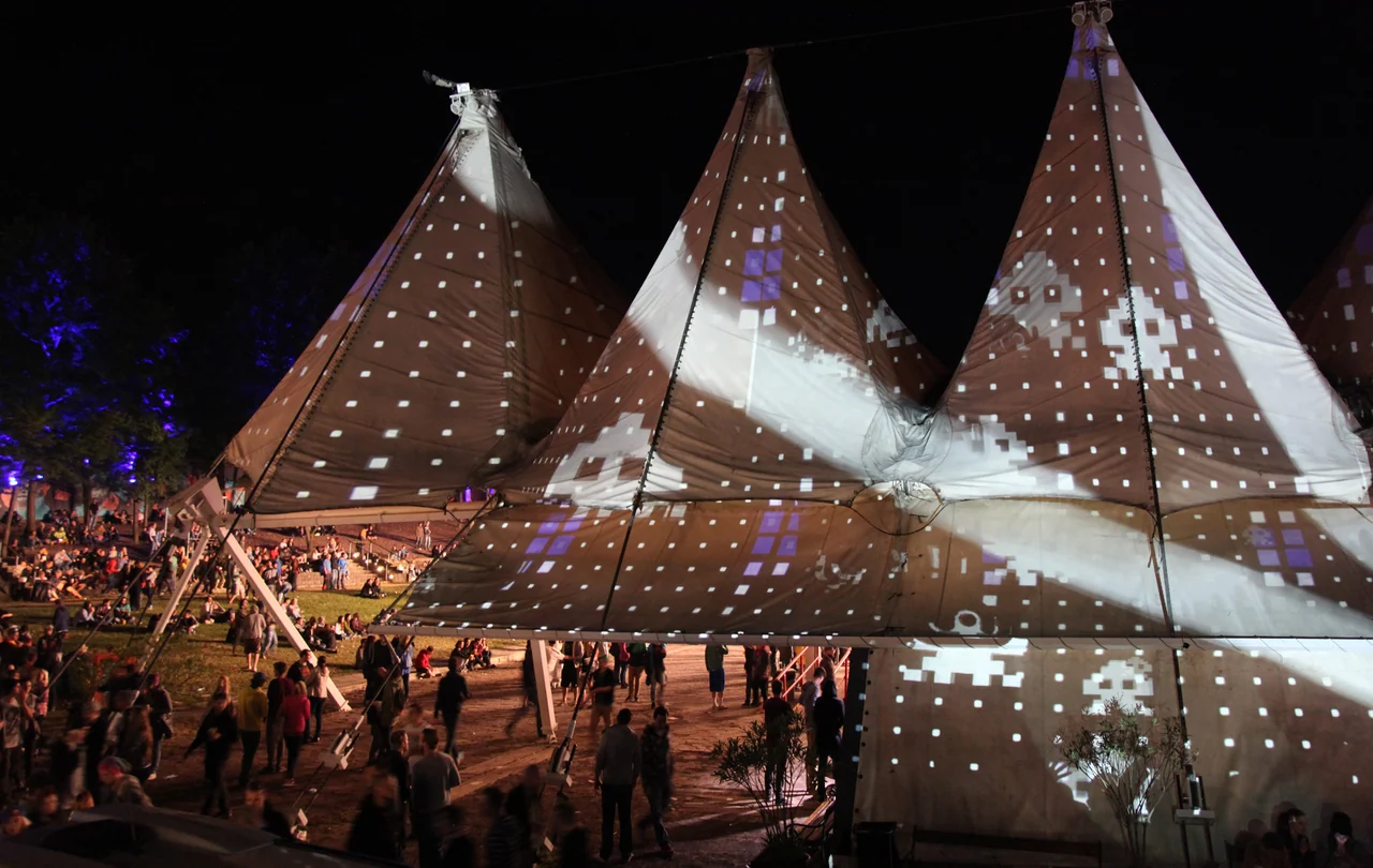 Seitliche Ansicht des Festivalzelts mit weißen Quadratmustern auf den Zeltspitzen