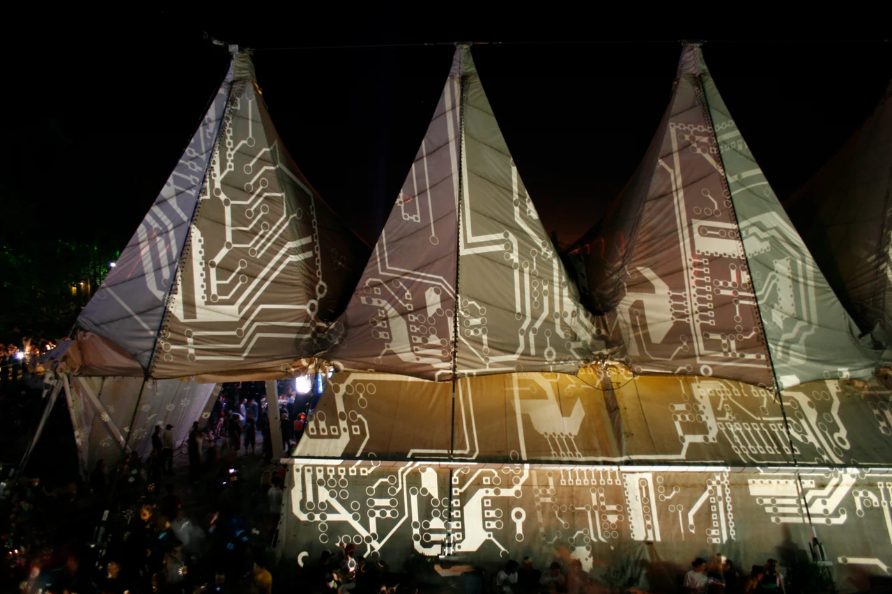 PANI-Projektion mit weißen Leiterbahnmustern auf dem Festivalzelt in Wiesen bei Nacht
