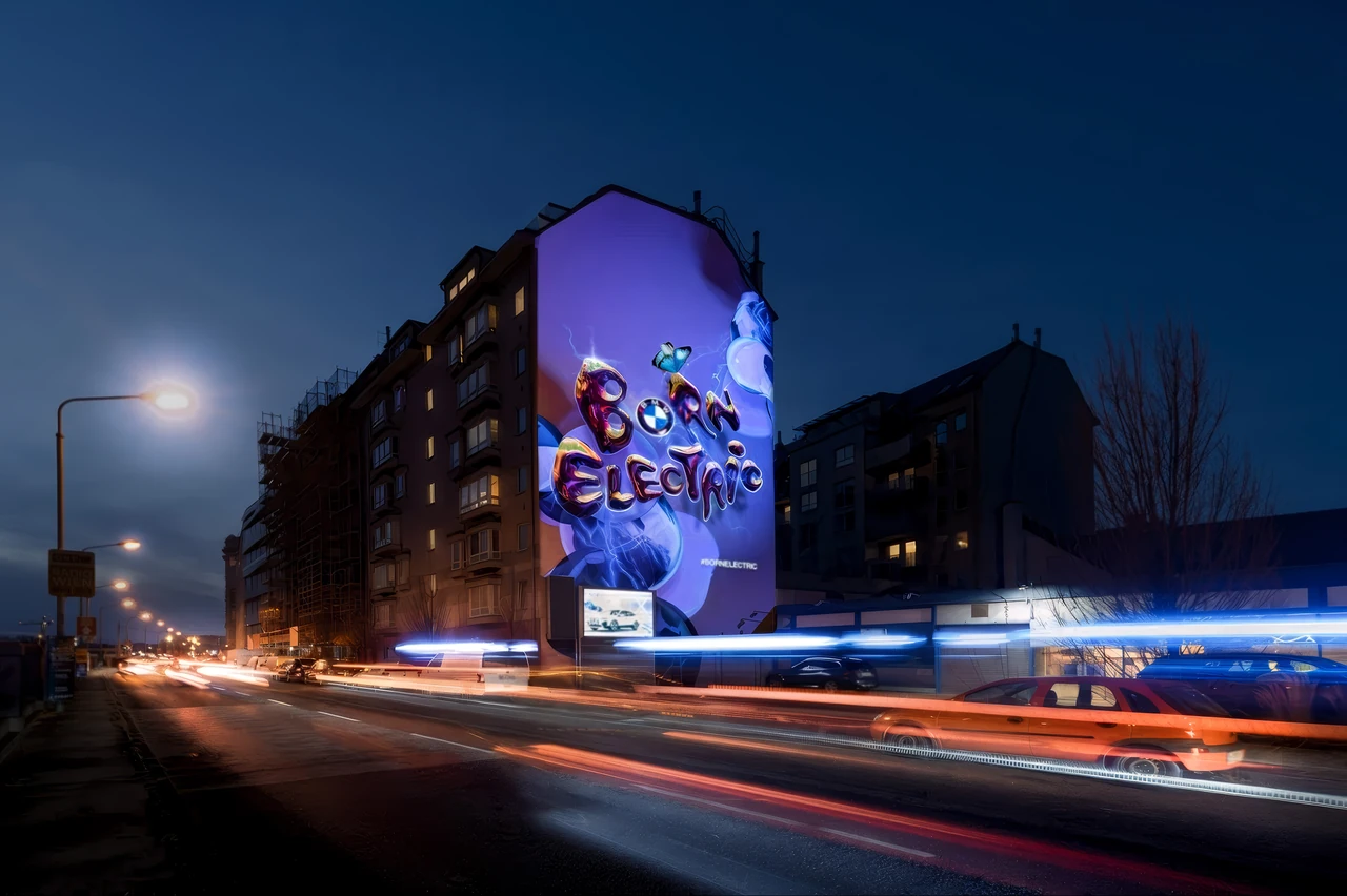 Straßenansicht mit beleuchteter Mural-Projektion und Verkehr – BMW - BORNELECTRIC, Linke Wienzeile, Wien, Österreich