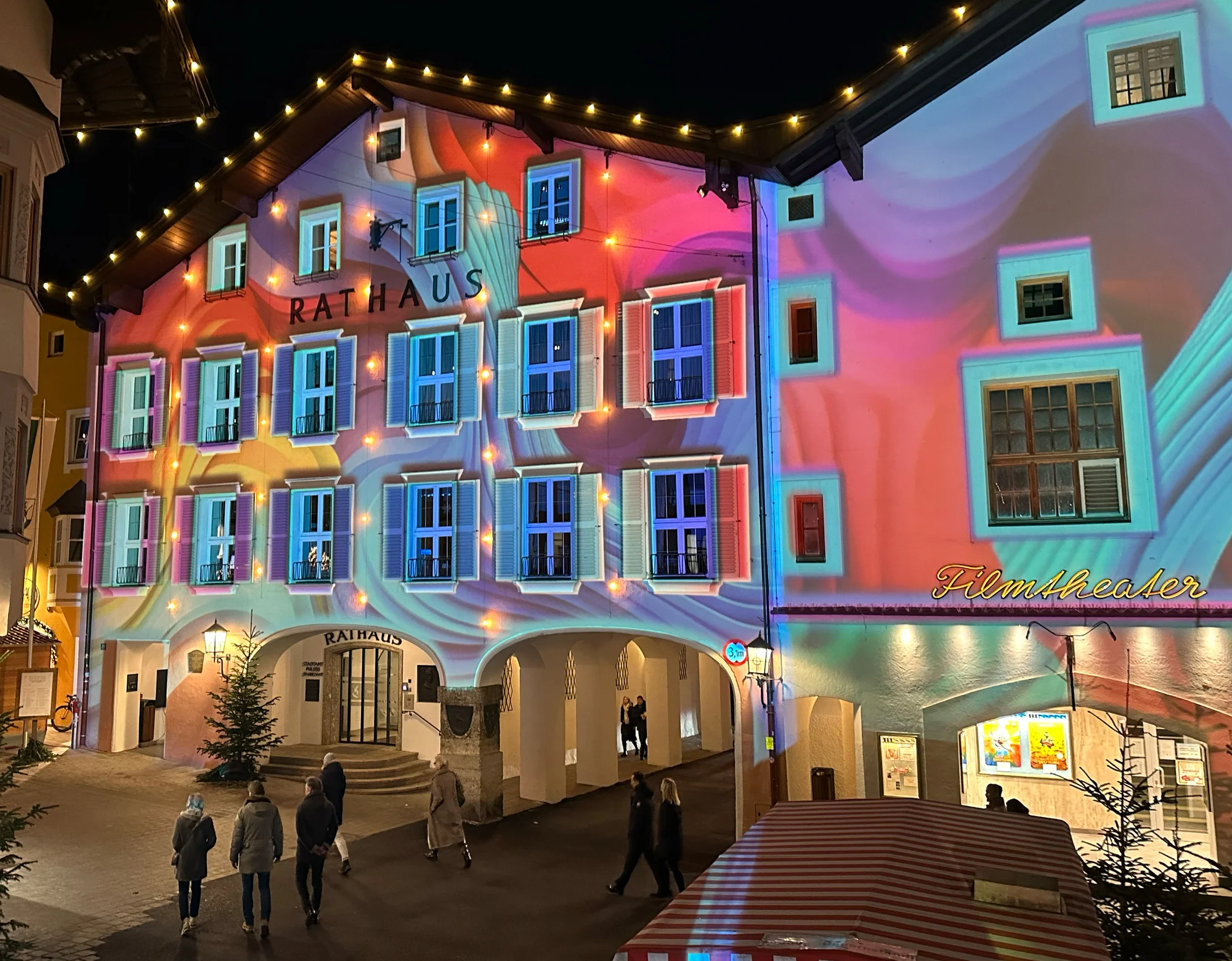 Side view of colourful facade projections with visitors in the foreground