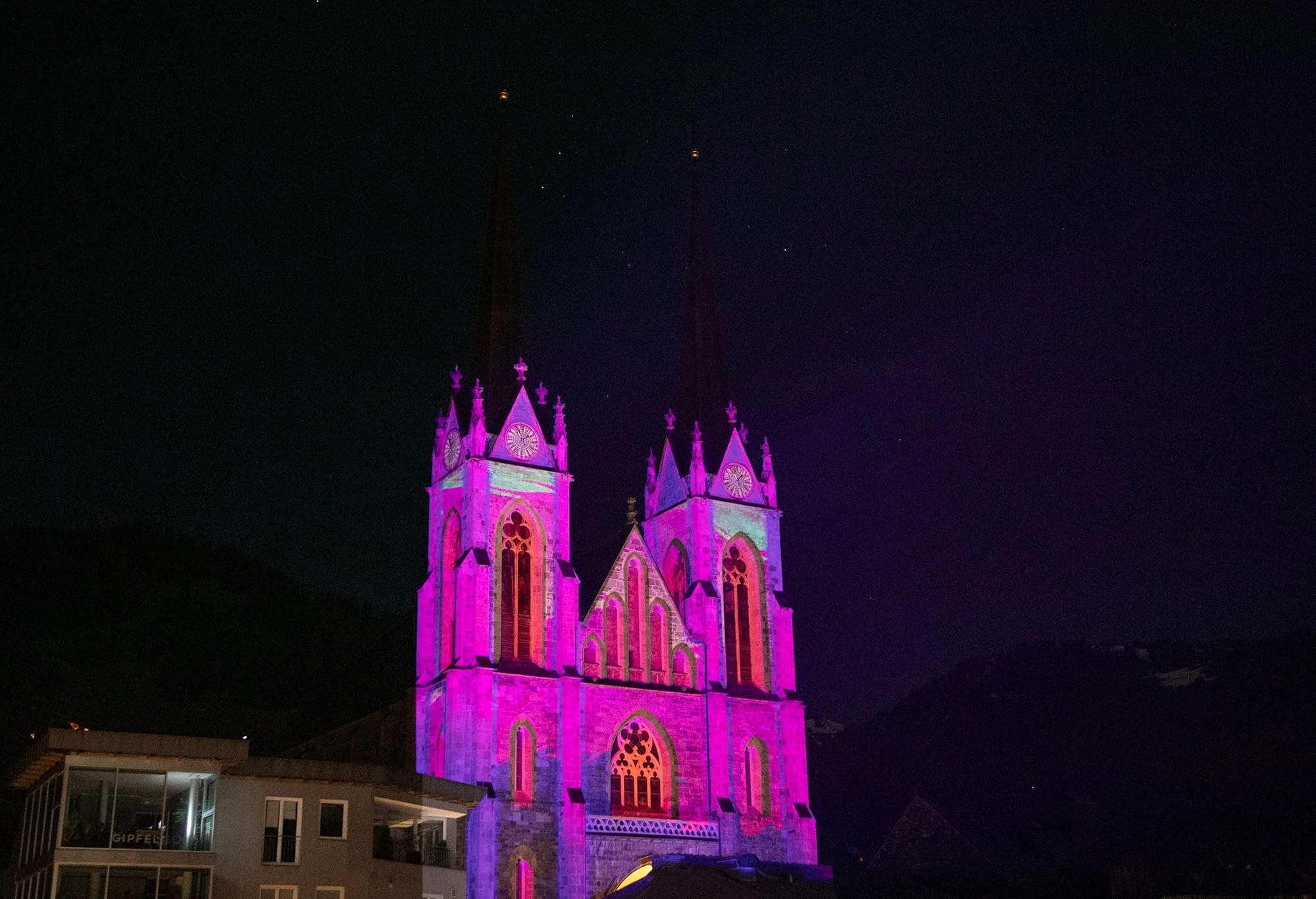 Magenta Videomapping auf den Türmen und dem Eingang des Doms