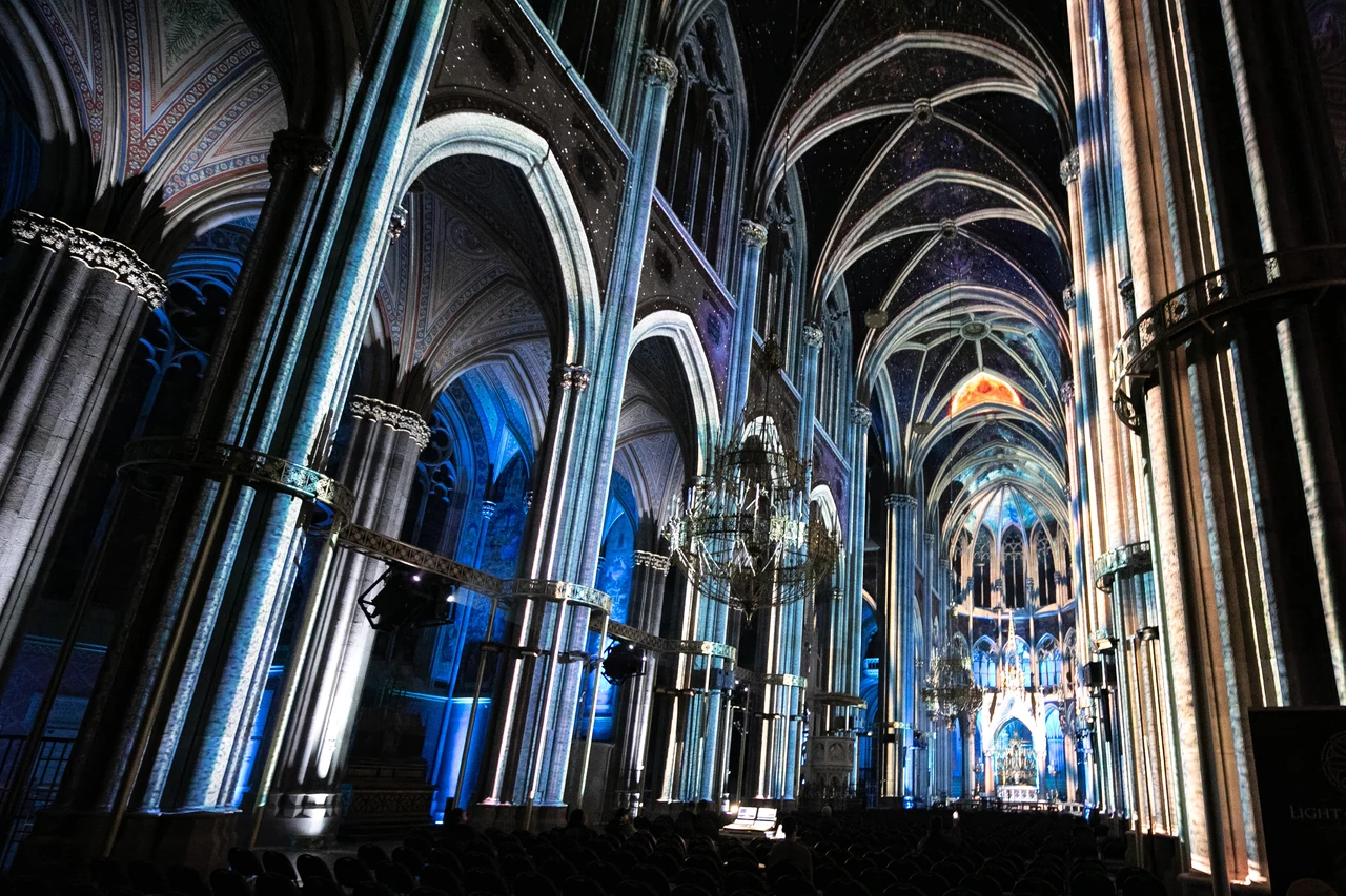 Blaue und goldene Projektionen entlang der Kirchengewölbe – LIGHT OF CREATION, Votivkirche, Wien, Österreich
