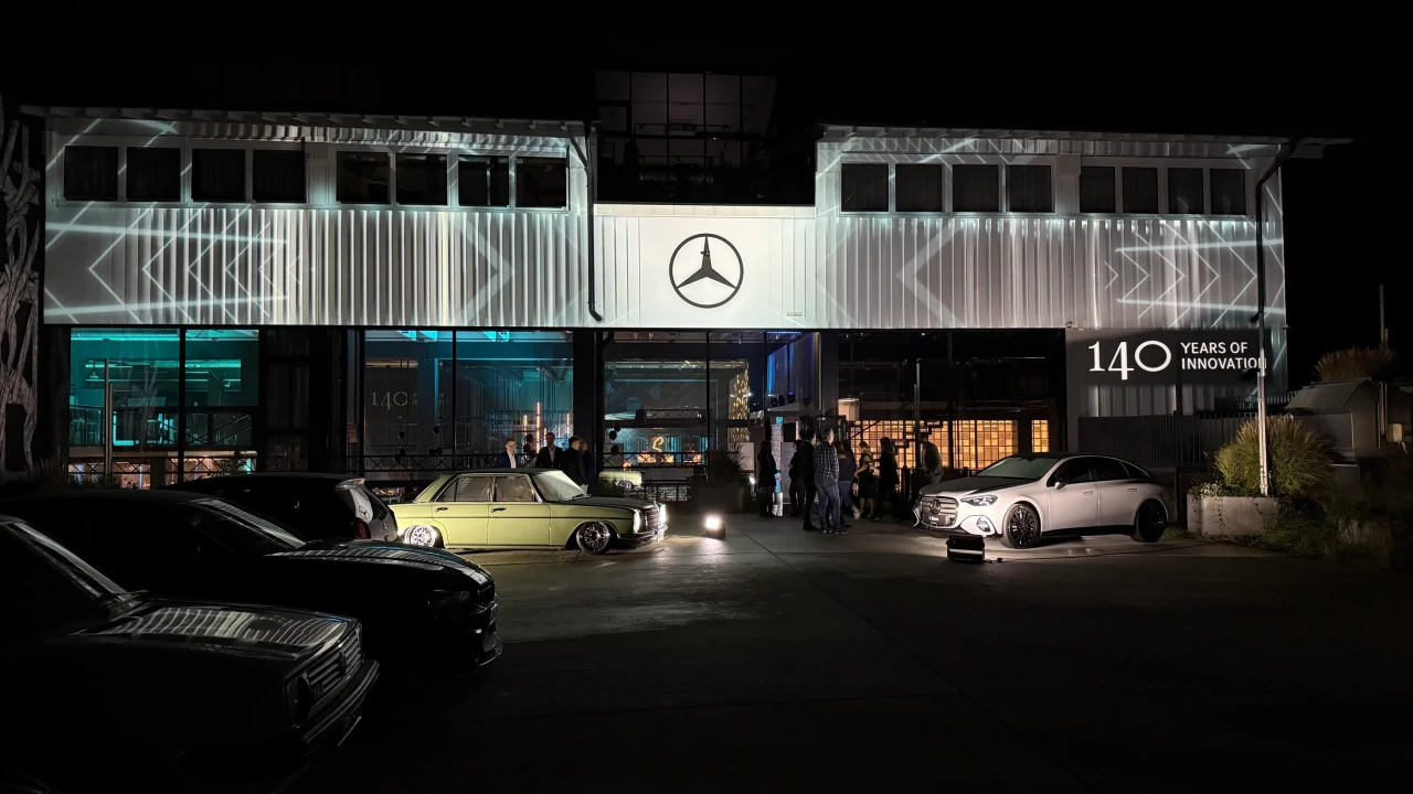 Vertikale weiße Streifen und Winkelmuster auf der Fassade, mit Mercedes-Stern über den ausgestellten Fahrzeugen
