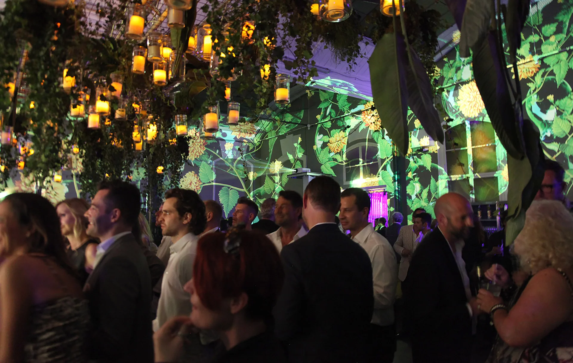 Guests under hanging lights in front of green wall projections