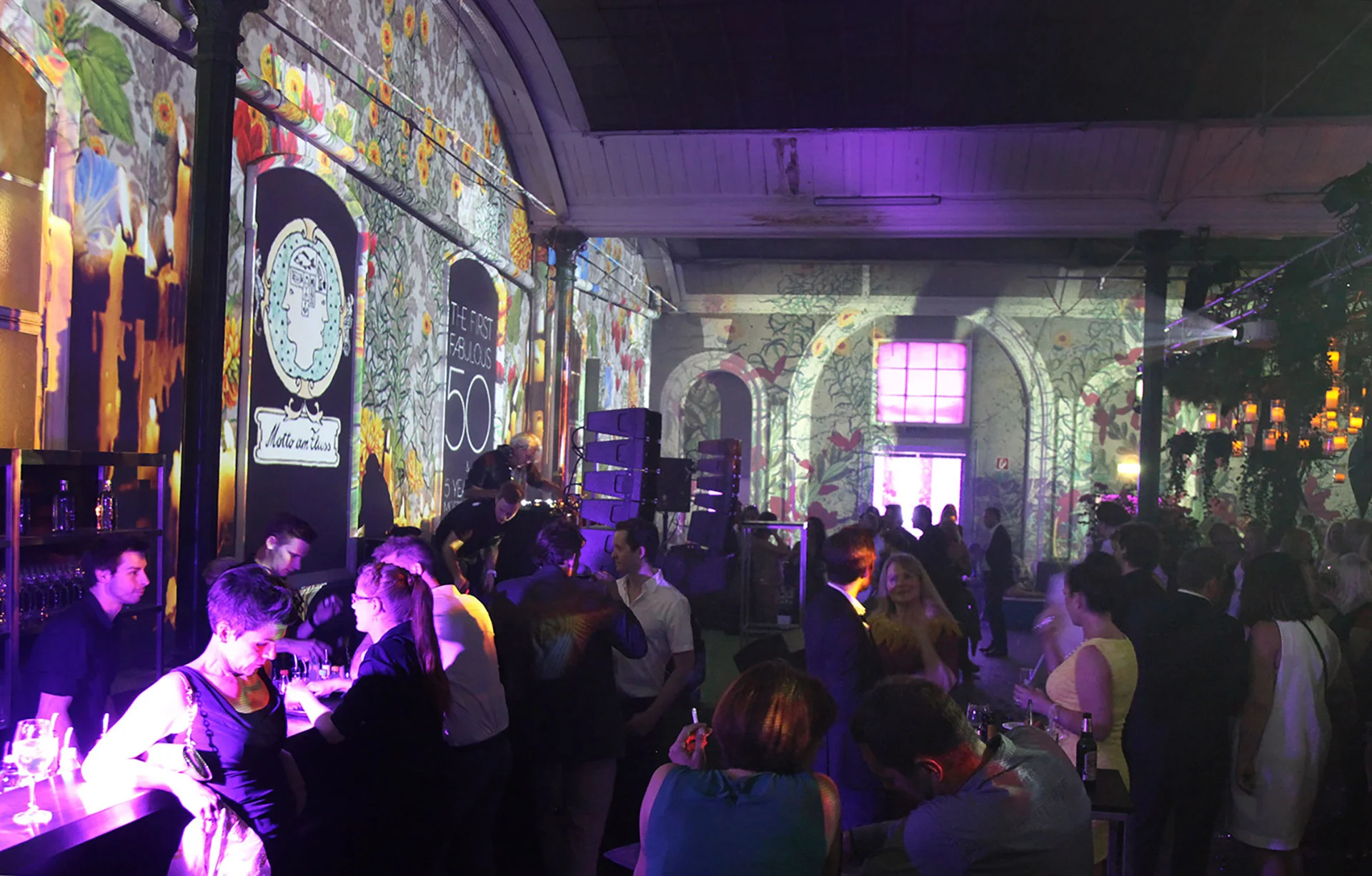Wide view of the event hall with projected plant motifs and violet light