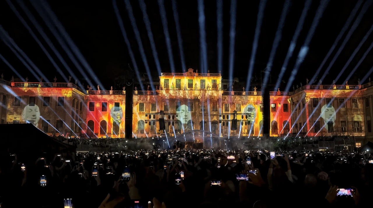 Konzertpublikum vor goldfarbenen Visuals und Lichtstrahlen am Schloss Schönbrunn