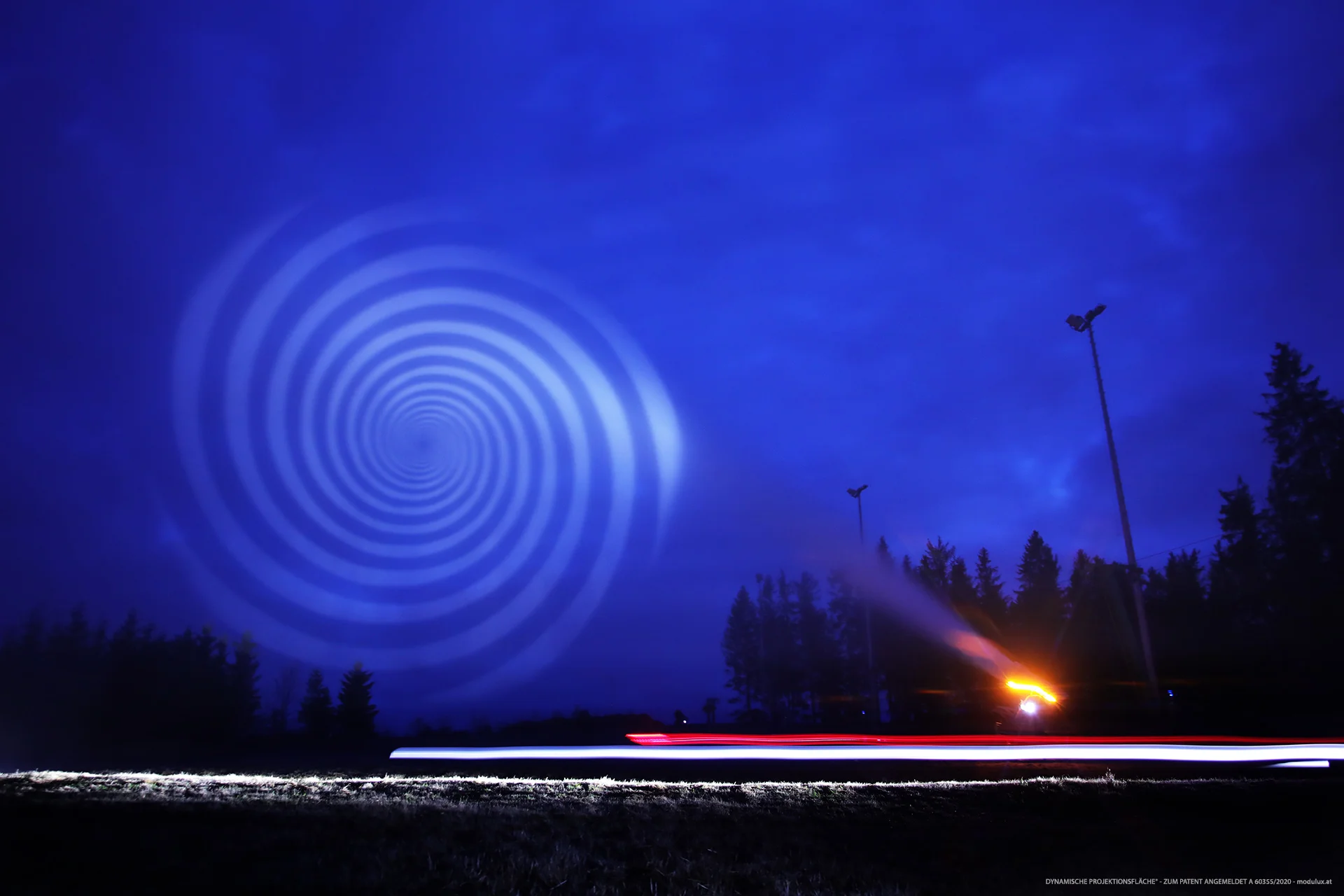 White spiral projected onto blue-lit water particles outdoors