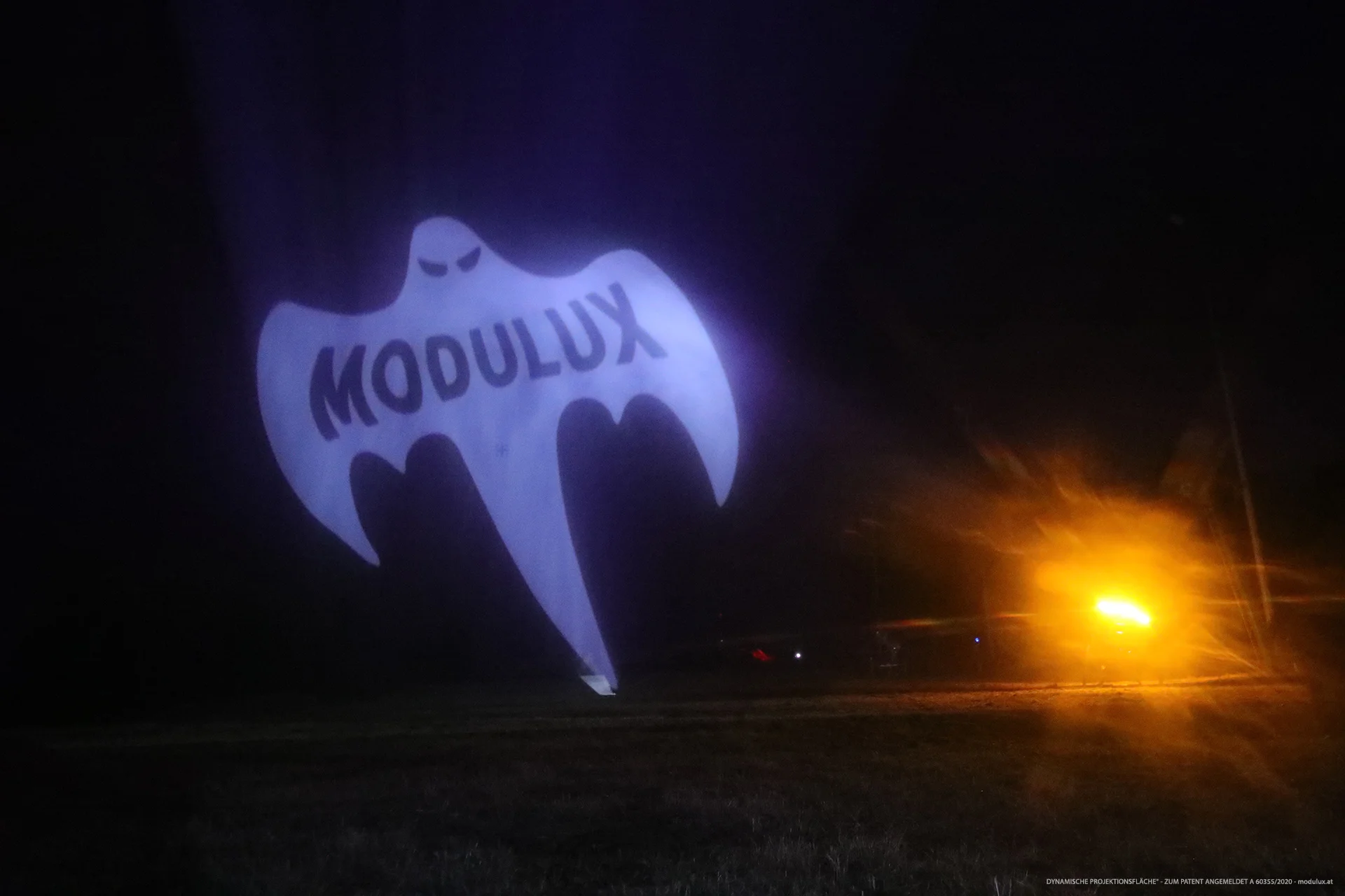 White MODULUX ghost projected onto water particles at night