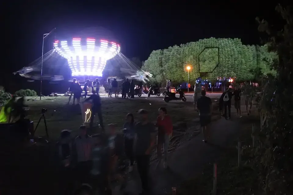 Grüne Projektionen in Baumkronen neben einem Fahrgeschäft – LIGHTHOUSE FESTIVAL 2017, Poreč, Kroatien