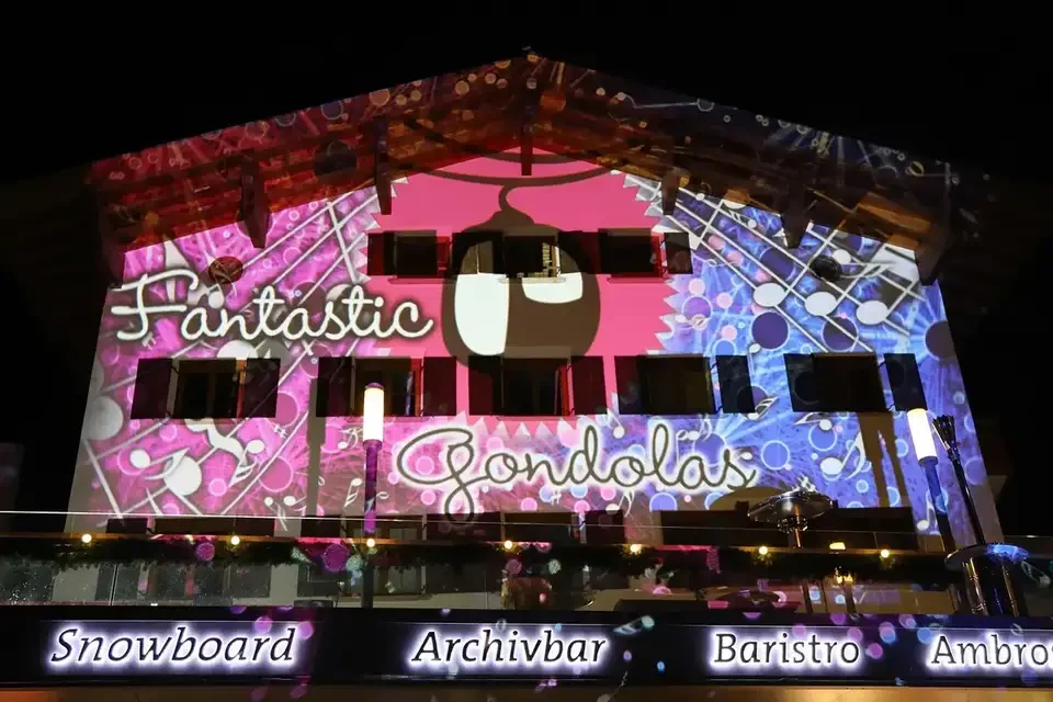 Pinkes Fassadenmapping auf eine Seilbahnstation bei Nacht – FANTASTIC GONDOLAS, Lech, Österreich