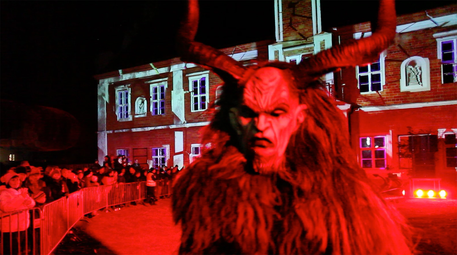 Krampusfigur vor der projizierten Rathausfassade und dem Publikum – Wachauer Advent, Videomapping in Spitz, Wachau, Österreich